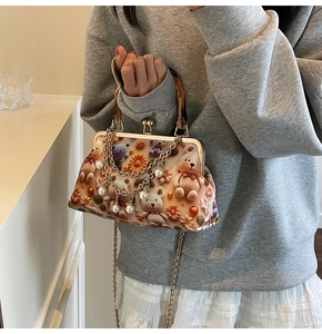 Detail of retro bear print bag featuring natural bamboo handle and pearl chain strap