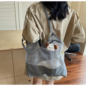 Detail of grey mesh tote bag with cute dog print and plush keychain on a casual model