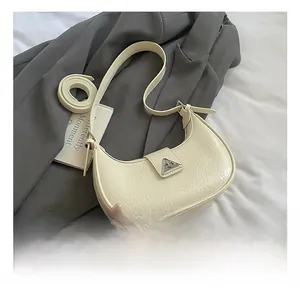 Close-up of cream crescent hobo bag with pleated leather texture and silver buckle