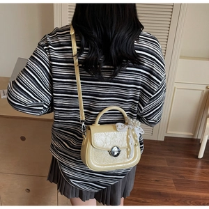 Détail du sac bandoulière jaune brillant avec noeud en dentelle blanche et pendentif perle