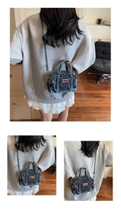 Detail of a washed denim mini crossbody bag with leather logo patch and adjustable strap