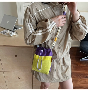 Close-up of a purple and yellow contrast drawstring crossbody bag with mesh texture