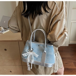 Detail of light blue denim bucket bag with lace bow and sparkling rhinestone accents