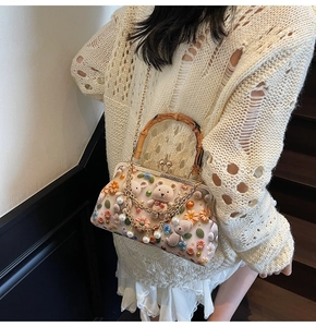 Detailed view of handmade knitted bears and floral beadwork on a pink shoulder bag