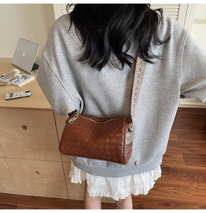 Close-up of brown woven leather texture on a shoulder bag with geometric jacquard strap
