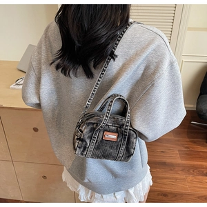 Detail view of a vintage dark grey washed denim mini crossbody bag on a model