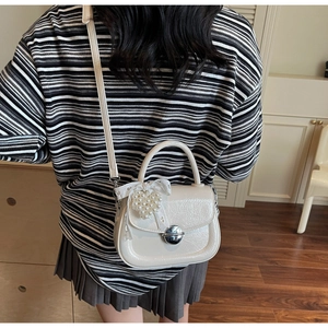 Détail du sac blanc crème avec pendentif cœur en perles et nœud en dentelle en intérieur