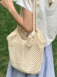 Off-white hand-woven tote bag with hollow diamond knit texture and tassel pendant