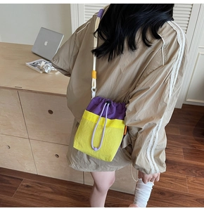 Detail of color-block drawstring bag with yellow mesh base and lilac shoulder strap