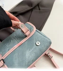 Detail of magnetic snap closure on blue denim and pink leather crossbody bag