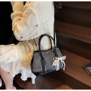 Detail of grey tweed bucket bag with lace bow and pearl pendant on a model