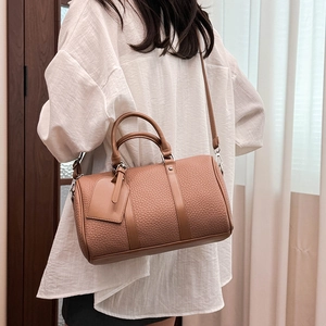 Detail of caramel lychee grain leather Boston bag worn by a model in a natural light setting