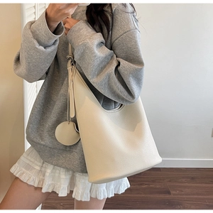 Detail of off-white Hobo bag with lychee grain leather and round pendant charm
