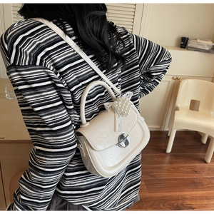 Détail du sac bandoulière crème avec texture cuir et breloque cœur en perles