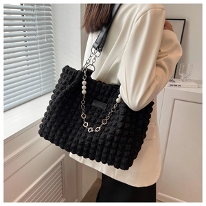 Detail of black popcorn texture tote bag with pearl flower chain and leather strap
