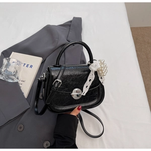 Détail du sac à main plissé noir avec fermoir argenté et breloque en perles et dentelle