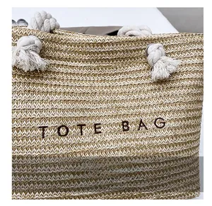 Detail of straw tote bag showing woven texture, cotton rope handles and tote bag embroidery