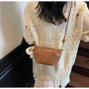Detailed back view of a brown leather crossbody bag with a white plush doll charm