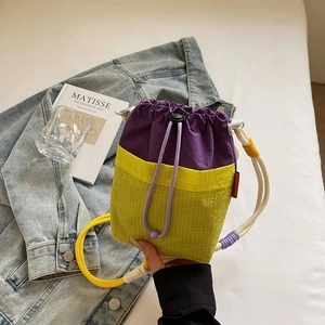 Detail of purple and neon yellow drawstring bucket bag with mesh pocket and braided strap