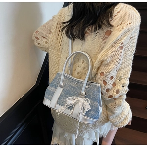 Detail showing blue glitter fabric bucket bag with a white lace bow and pearl pendant
