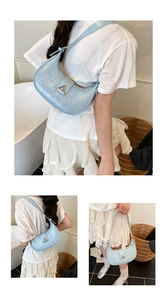 Close-up of light blue patent leather crescent bag with silver triangle metal buckle