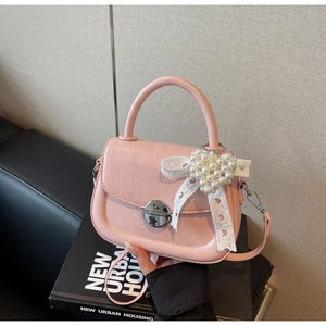 Détail du sac à main rose en cuir plissé avec fermoir argenté et breloque perle