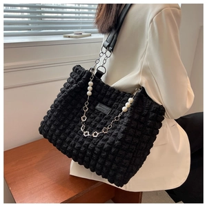 Detail of black pleated bubble texture tote bag with pearl and floral metal chain charm