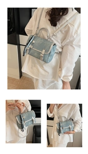 Detail view of light blue denim crossbody bag with star charm and silver buckles