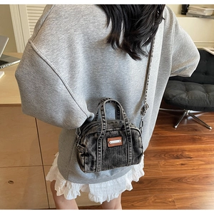 Detailed close-up of retro washed denim handbag with dual zippers and leather patch