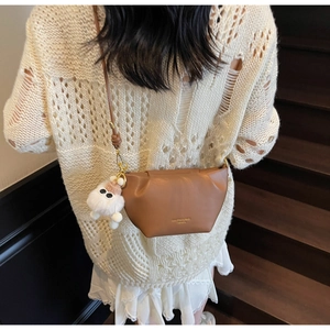 Brown leather crossbody dumpling bag with white plush monster charm and gold hardware