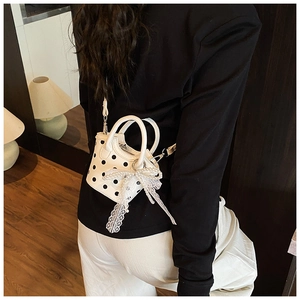 Detailed close-up of a mini polka dot crossbody bag with lace bow and pearl charm accents