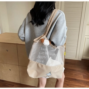 Detailed view of beige mesh tote bag with canvas base and plush puppy charm on model