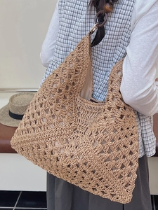 Large woven straw tote bag with crochet details and wooden ring straps for beach vacations