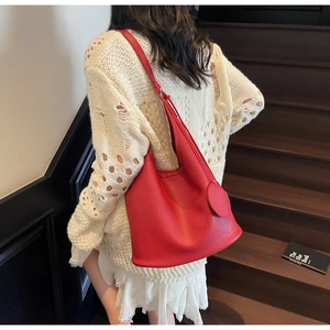 Detail of red pebbled leather hobo bag worn on shoulder by model on stairs