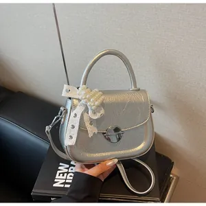 Sac à main argenté métallisé avec breloque perle et dentelle et fermoir rond sur cuir noir