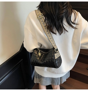 Detail showing black woven pillow bag with ethnic style canvas strap and gold hardware
