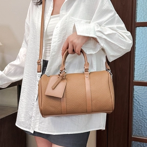 Close-up of brown litchi grain leather Boston bag with round handles and a detachable strap