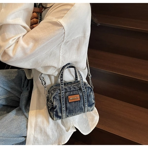 Detail of distressed denim crossbody bag with brown leather patch on vintage texture