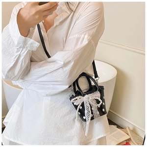 Detailed shot of black polka dot mini bag featuring pearl beads and white lace bow detail