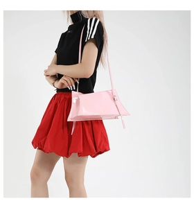 Detail shot of a pink patent leather shoulder bag with unique geometric folding design
