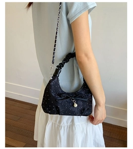 Close-up of black crescent floral shoulder bag with a bow and elegant pearl pendant
