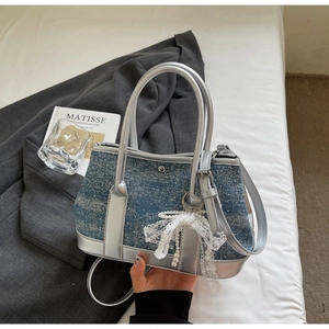 Detail of blue denim bucket bag with silver leather trim and white lace bow accessory