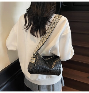 Detail of black woven shoulder bag with a stylish geometric patterned wide strap