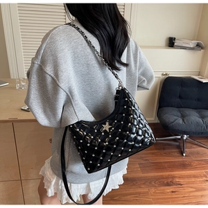 Détail du sac en cuir verni noir avec matelassage en losange et boucle étoile argentée
