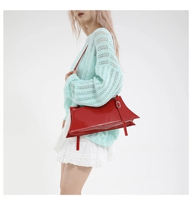 Detail view of glossy red rectangular handbag with sharp edges and side metal buckle