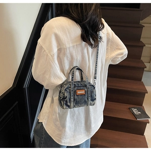 Close-up of a distressed denim mini handbag with brown leather accents and silver hardware