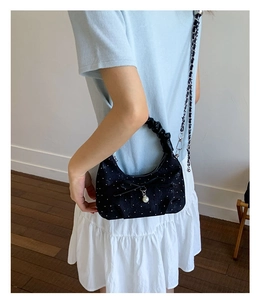Polka dot half-moon shoulder bag with bow and pearl detail shown on a model