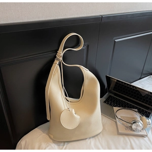 Detailed macro view of cream pebbled leather hobo bag with a matching round coin pouch charm