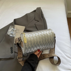 Detail of silver woven pillow bag featuring golden hardware and colorful patterned strap