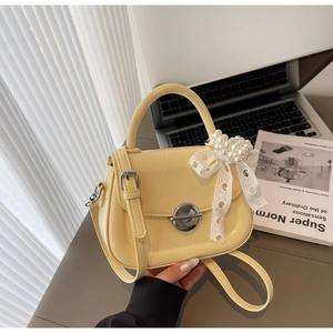 Détail du petit sac jaune clair avec nœud en dentelle perle et fermoir métallique